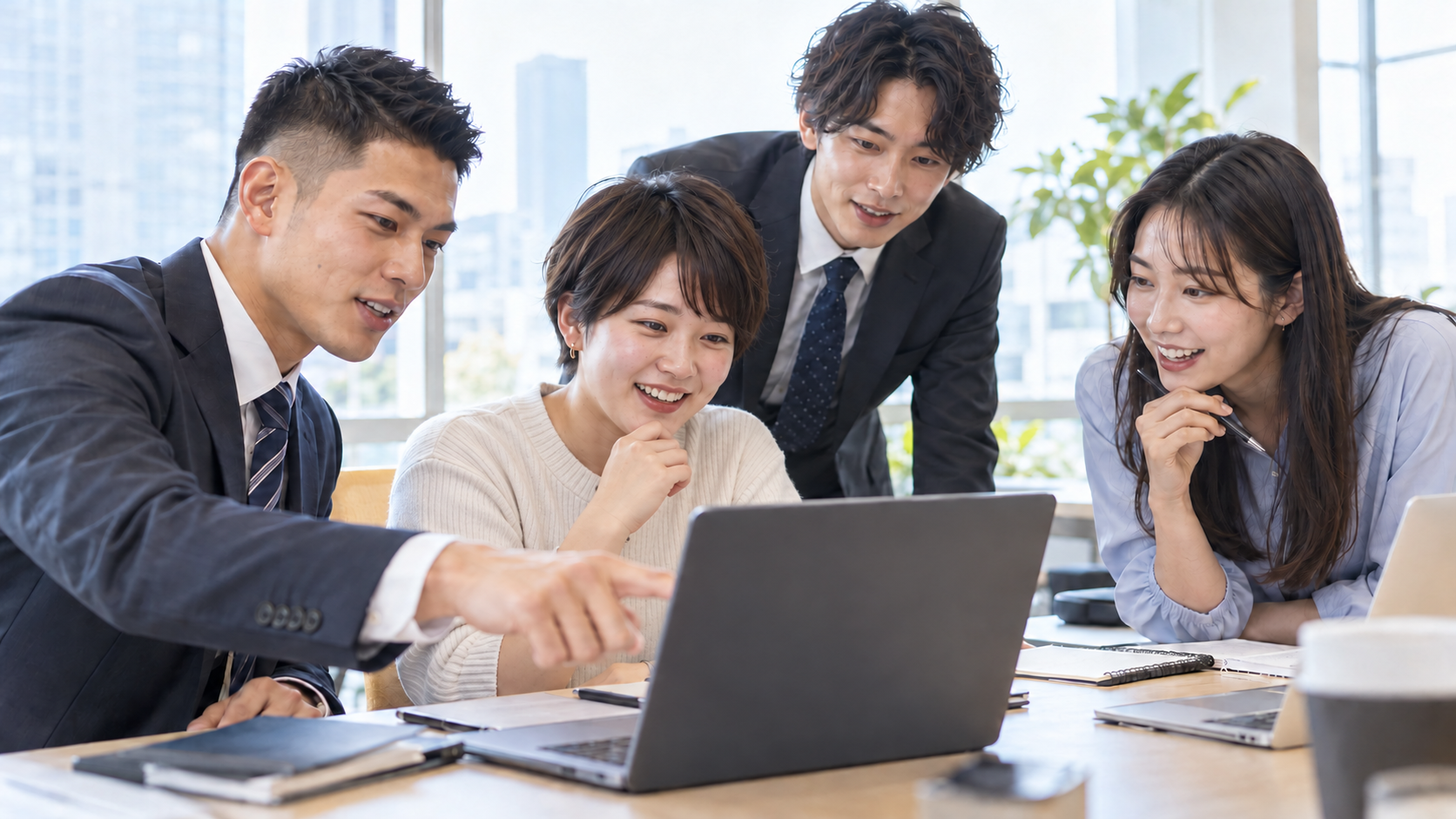 体型や顔立ちの異なる20代前半のメンバーがノートパソコンを囲みIT研修に取り組む様子