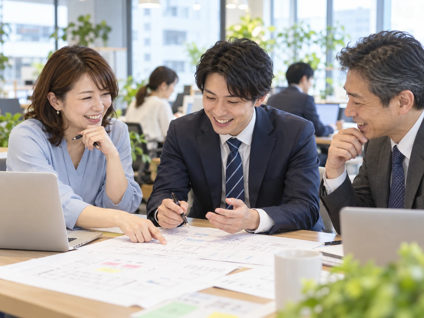技術リーダーと仲間が紙の設計案を広げ、実現方法を前向きに検討する情景